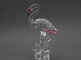 une figurine de flamant rose en verre transparent, dotée d'un bec rose, posée sur un socle transparent