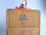 a small wooden box with a red handle and a metal letter on it