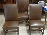 three brown leather chairs sitting on top of a tiled floor