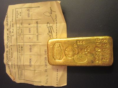 un lingot d'or posé sur un bout de papier à côté d'un ticket de caisse