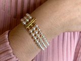 the woman is wearing a pink shirt and a pearl bracelet