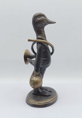 statue en bronze représentant un canard tenant une trompette, sur fond blanc