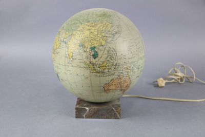 un globe terrestre posé sur un socle, auquel est attaché un cordon