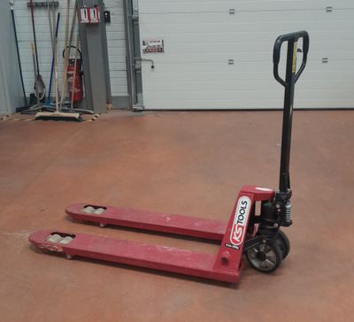 un chariot élévateur rouge garé dans un garage, avec la porte du garage en arrière-plan