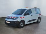 La camionnette blanche est garée dans une grande pièce ; elle porte une bande rouge et blanche sur le côté.