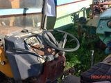 a tractor that is sitting in the grass next to a boat