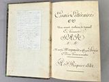 un livre ouvert, dont une page est recouverte d'une écriture manuscrite, posé sur une table