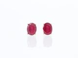 une paire de boucles d'oreilles à clous ornées de rubis, posées sur un fond blanc