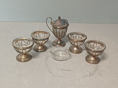 un service à thé en argent, avec des tasses et des soucoupes, posé sur une table