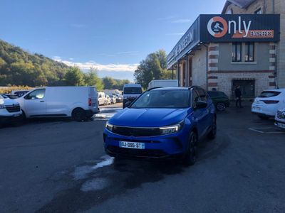 La voiture bleue est garée devant un immeuble sur lequel est accrochée une pancarte indiquant uniquement