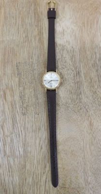 montre-bracelet avec bracelet en cuir noir et cadran blanc sur fond en cuir de vachette