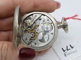 a person holding a silver pocket watch in their hand