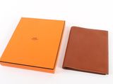 un portefeuille en cuir orange et marron à côté d'une boîte orange