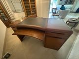 a wooden desk with a glass cabinet in the corner