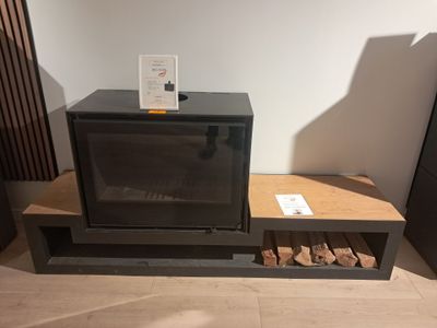 un micro-ondes noir posé sur une étagère, à côté d'une pile de bois