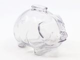 une figurine en verre représentant un cochon, posée sur une surface blanche