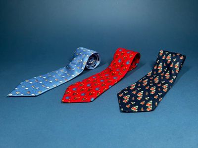 four different colored ties are lined up on a blue surface