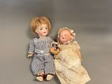 two dolls sitting next to each other on a gray surface