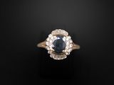 a close up of a ring with a blue sapphire and white diamonds