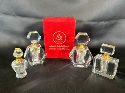 trois petits flacons de parfum en verre, présentés dans une boîte rouge posée sur un fond noir