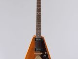 une guitare électrique orange suspendue à une ficelle sur un mur blanc