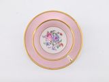 a close up of a pink and gold plate on a white surface
