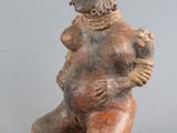 une vieille figurine représentant un homme assis sur un tabouret
