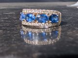 a close up of a blue and white diamond ring on a table