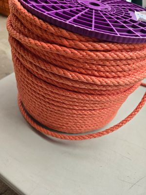 une corde orange surmontée d'une bobine violette, posée sur une table