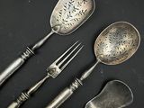 trois cuillères et une fourchette en argent sur une surface noire