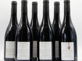 six bottles of wine are lined up in a row on a white surface