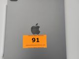 un iPad d'Apple orné d'un autocollant, posé à côté d'un stylo