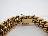gros plan d'un bracelet en or sur une surface blanche