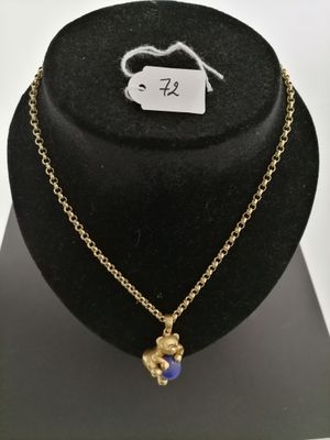 a gold necklace with a blue bead on a black mannequin
