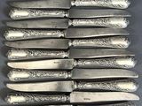 six couteaux en métal argenté sont alignés en rang sur une table