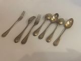 six silver spoons and a fork on a white surface