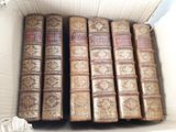 several old books are in a cardboard box on a table