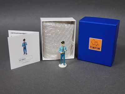 une petite figurine représentant un homme en costume bleu, dans une boîte bleue