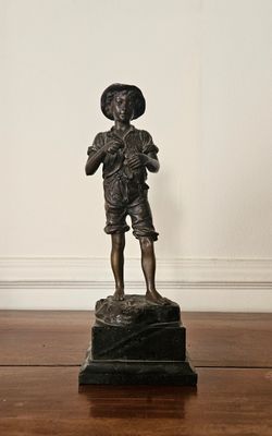 une statue représentant un garçon debout sur un socle