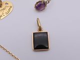 two gold necklaces and a pendant with a black stone