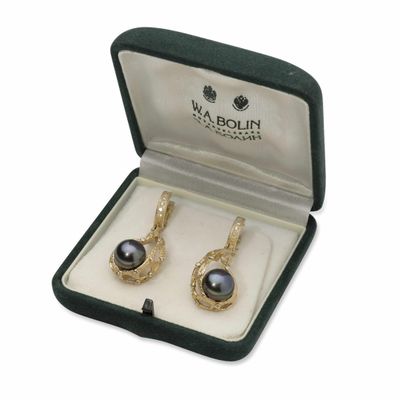une paire de boucles d'oreilles en perles noires, présentée dans un coffret cadeau sur fond blanc