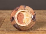 a brown and white vase sitting on a wooden table