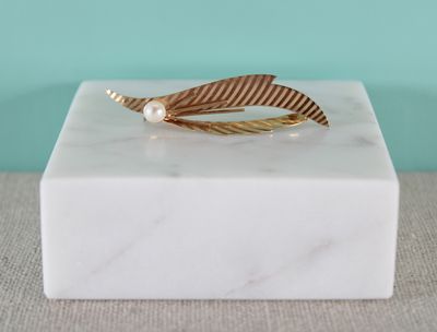 a close up of a white marble block with a gold feather on it