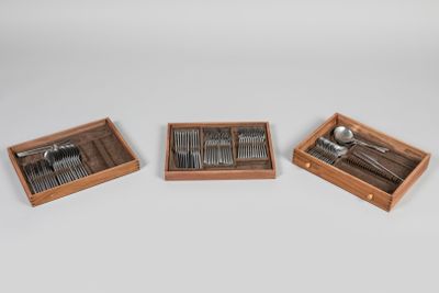 trois plateaux en bois contenant des fourchettes et des cuillères, posés sur une surface blanche