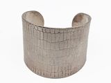 un gros plan d'un bracelet manchette en argent sur fond blanc
