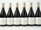 six bouteilles de vin sont alignées sur une surface blanche