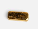 a gold bar on a white surface with a white background