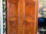 une armoire en bois dans une pièce au papier peint à motifs floraux