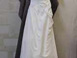 a wedding dress hanging on a hanger in front of a brick wall