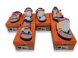 Plusieurs paires de sandales sont posées sur des cartons orange.